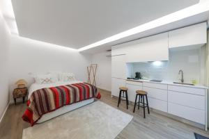 a white bedroom with a bed and a kitchen at Estúdio Cândida, One place … in Nazaré