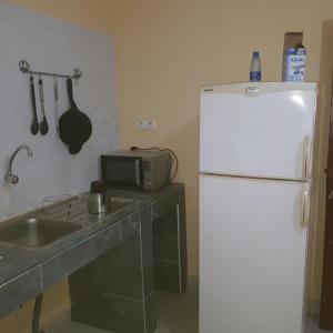 La cuisine est équipée d'un évier et d'un réfrigérateur blanc. dans l'établissement ZAC MBAO - Cité enseignants, à Kammba