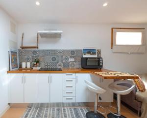 a kitchen with white cabinets and a counter with a microwave at Tiny House By Casa Maui in Corralejo
