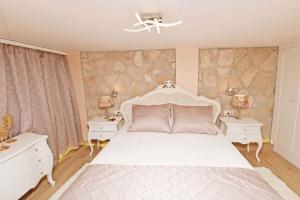 ein Schlafzimmer mit einem großen weißen Bett mit zwei Nachttischen in der Unterkunft Holiday home in Dubrovnik 43524 in Dubrovnik