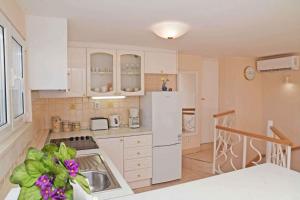eine Küche mit weißen Schränken und einem weißen Kühlschrank in der Unterkunft Holiday home in Dubrovnik 43524 in Dubrovnik