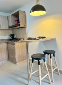 een keuken met 2 krukken en een tafel met een licht bij Apartamento Moderno Estelar in Sabaneta