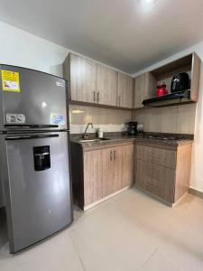 een keuken met een roestvrijstalen koelkast en houten kasten bij Apartamento Moderno Estelar in Sabaneta