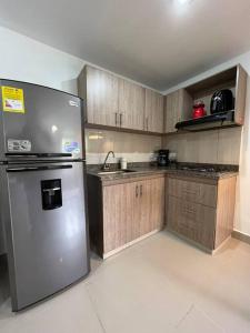 a kitchen with a stainless steel refrigerator and wooden cabinets at Apartamento Moderno Estelar in Sabaneta