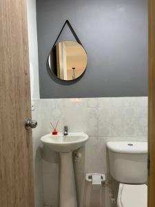 een badkamer met een wastafel, een toilet en een spiegel bij Apartamento Moderno Estelar in Sabaneta