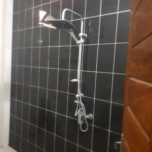 y baño con ducha y azulejos negros. en ZAC MBAO - Cité enseignants, en Kammba