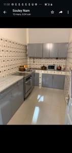 uma cozinha com armários cinzentos e um piso branco em Al Rayane em Dakar