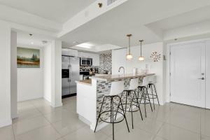 a kitchen with white cabinets and a bar with stools at Stunning Bayview! Large condo in beachfront resort with shared pools and jacuzzi in South Padre Island