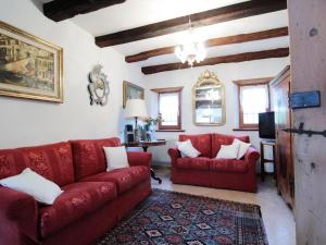 - un salon avec un canapé rouge et deux chaises dans l'établissement Beautiful holiday home in Chies d'Alpago with garden, à Chies dʼAlpago
