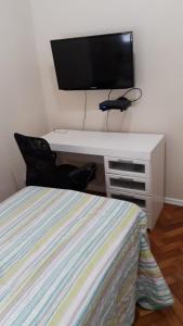 een slaapkamer met een bed en een bureau met een televisie bij Quarto no Coração da Tijuca in Rio de Janeiro