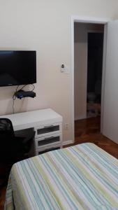 1 dormitorio con 1 cama y escritorio con TV en Quarto no Coração da Tijuca, en Río de Janeiro