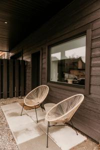 two chairs sitting on a porch next to a window at Drift West Coast Getaway in Ucluelet