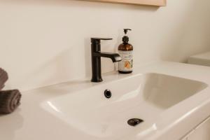 a bathroom sink with a bottle of soap on it at Drift West Coast Getaway in Ucluelet