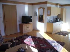 a living room with a tv and a table and a kitchen at Ferienwohnungen Falger in Berwang