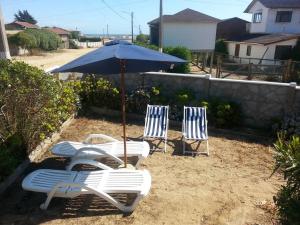 trzy krzesła ogrodowe i parasol na piasku w obiekcie Casa en Consistorial w mieście El Tabo