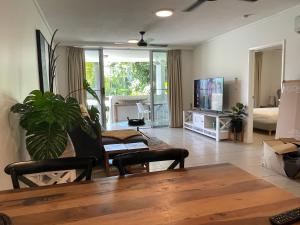 a living room with a table and chairs and a tv at Tropical Luxe Apartment in Townsville