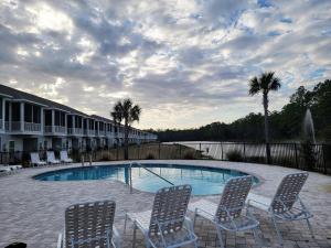 Una piscina con tres sillas al lado de un edificio. en Kara Lake 36, en Santa Rosa Beach