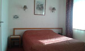 a bedroom with a bed with a red comforter and a window at Hotel Val Saint Hilaire in Givet