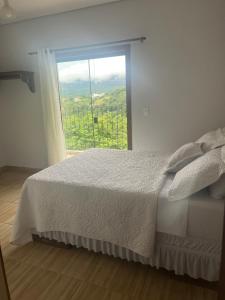 ein Schlafzimmer mit einem Bett und einem großen Fenster in der Unterkunft Casa Nascimento Vista Panorâmica Serra São José in Tiradentes