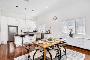 une cuisine avec des placards blancs et une table et des chaises en bois dans l'établissement Hyde Park Vista Spacious 3br Home, à Perth