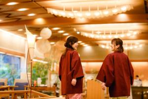 Dos mujeres en batas de graduación de pie en una habitación en Hatori, en Kaga