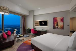 - une chambre avec un lit, un bureau et un canapé dans l'établissement Hard Rock Hotel Shenzhen, à Shenzhen