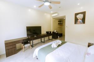 a bedroom with a bed and a desk and a television at Bohol Cattleya Resort in Panglao