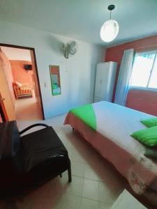 een slaapkamer met een bed en een stoel erin bij CASA HOST Las Grutas in Las Grutas