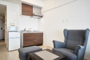 a living room with a chair and a kitchen at New Normal Hotel in NAGO ニューノーマルホテルイン名護 in Nago
