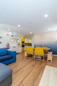 a living room with a blue couch and yellow chairs at Dude Beach Hostel in Figueira da Foz