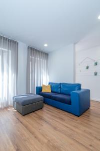 um sofá azul e um repousa-pés numa sala de estar em Dude Beach Hostel em Figueira da Foz