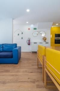 a living room with a blue couch and glasses on the wall at Dude Beach Hostel in Figueira da Foz