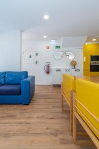 uma sala de estar com um sofá azul e óculos na parede em Dude Beach Hostel em Figueira da Foz