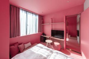 东京toggle hotel suidobashi TOKYO的粉红色的房间,配有床和电视 更多37张照片