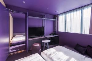 a purple room with two beds and a tv at toggle hotel suidobashi TOKYO in Tokyo