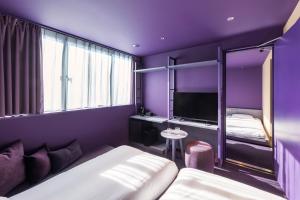 Habitación púrpura con cama y TV en toggle hotel suidobashi TOKYO en Tokio