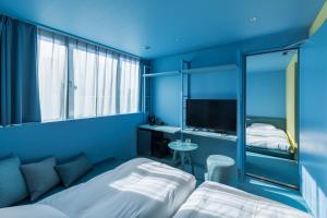 a blue room with two beds and a television at toggle hotel suidobashi TOKYO in Tokyo