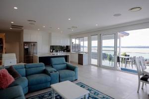 a living room with a blue couch and a kitchen at Spectacular water views & entertaining spaces in Corlette