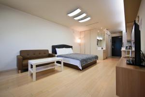 ein Schlafzimmer mit einem Bett, einem Sofa und einem TV in der Unterkunft Prime Guesthouse in Incheon