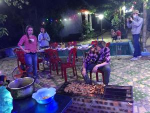 a group of people standing around a fire grill at Cat Ba Countryside Homestay in Cat Ba