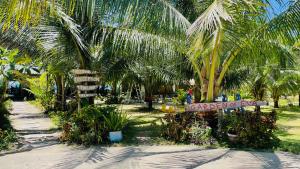 Footprints Beach Resort في Agpudlos: حديقة بها أشجار نخيل وعلامة