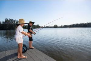 a woman and a child fishing on a dock at Discovery Parks - Forster in Tuncurry