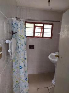 a bathroom with a shower curtain with a toilet at Finca la mora in Morelia