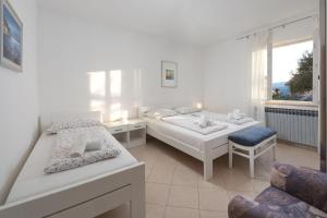 een witte slaapkamer met 2 bedden en een stoel bij Apartments Marina in Rabac