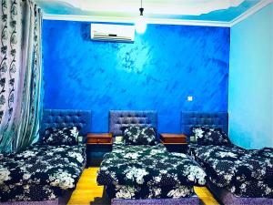 two beds in a room with a blue wall at Galaxy Apartments in Aqaba