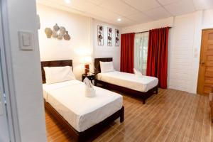 um quarto de hotel com duas camas e cortinas vermelhas em MADISON GARDEN AND RESIDENCES em Panglao