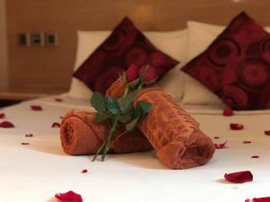 a teddy bear with a flower on a bed at The Room Hotel in Miri