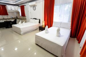 duas camas num quarto com cortinas vermelhas em MADISON GARDEN AND RESIDENCES em Panglao