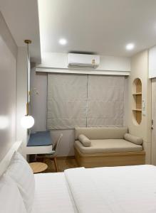 a bedroom with a bed and a couch and a heater at Moon House BKK Room 3B in Amphoe Phra Khanong