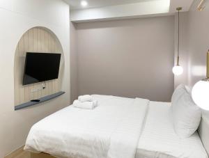 a white bedroom with a bed and a tv at Moon House BKK Room 3B in Amphoe Phra Khanong